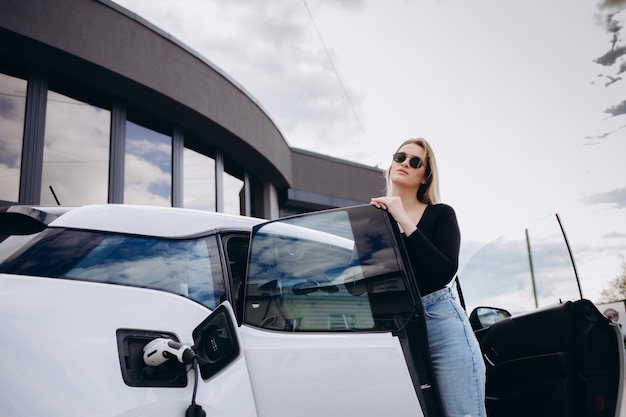 Donna che carica l&#39;auto elettrica alla stazione di gas elettrica