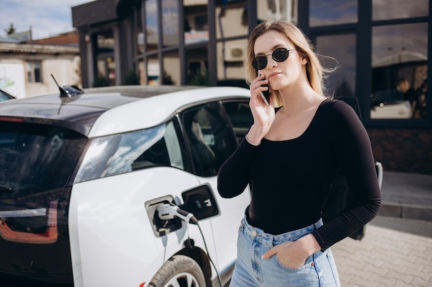 Donna che carica l&#39;auto elettrica alla stazione di gas elettrica