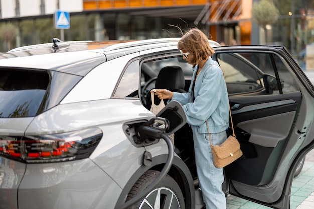 Donna che carica l'auto elettrica mentre fa la spesa