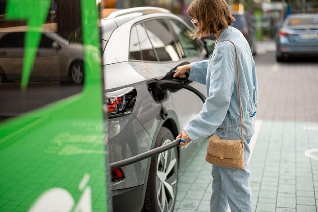 Donna che carica la sua auto con un caricabatterie pubblico