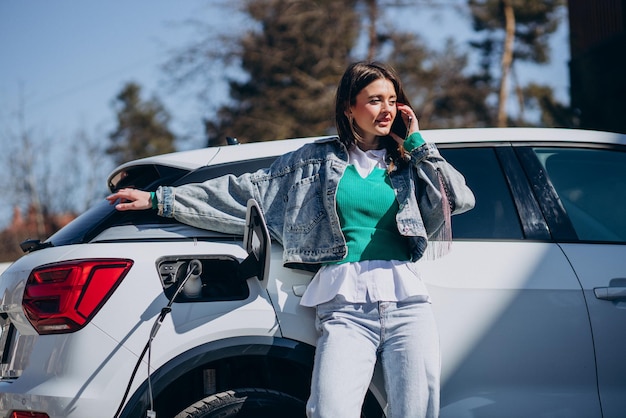 Donna che carica la sua auto elettrica con la pistola di ricarica