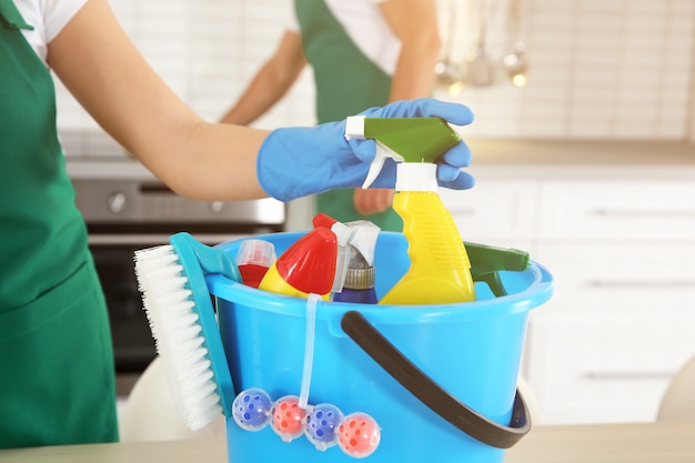 Donna che cattura detergente dal secchio con detergenti, primo piano