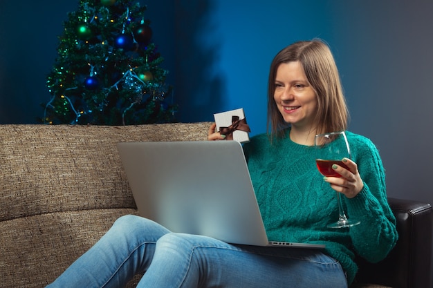 Donna che celebra la vigilia di Natale con i parenti tramite una chiamata online su un laptop Boxing day