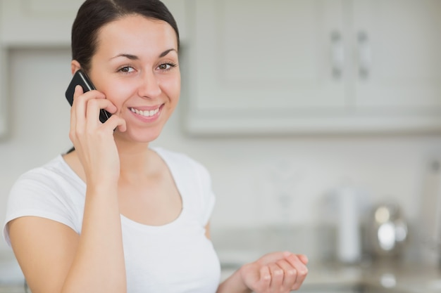 Donna che chiama con il cellulare in cucina