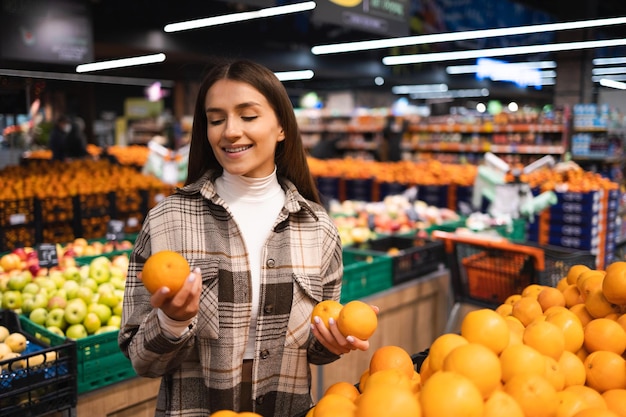 Donna che compra arance fresche al supermercato