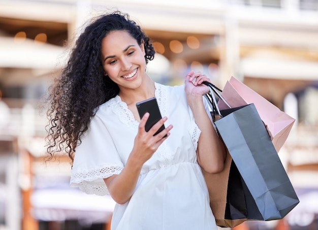 Donna che compra e smartphone o che scrive in città affare al dettaglio e cliente con borse per la vendita online notifica Internet tech e e-commerce app per l'offerta al consumatore e speciale del venerdì nero