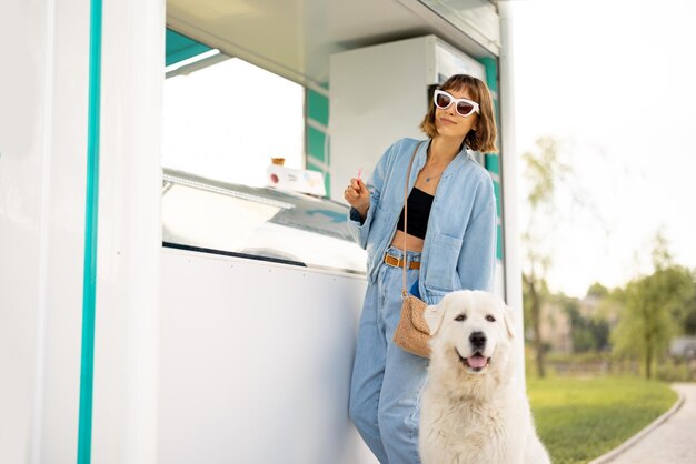 Donna che compra il gelato al negozio mentre cammina con un cane all'aperto