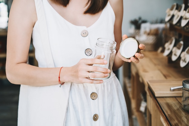 donna che compra in un negozio di alimentari senza plastica ragazza con sacchetto di cotone riutilizzabile in un negozio a zero rifiuti waste