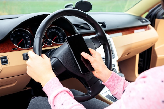 donna che comunica sul cellulare mentre si guida l'auto