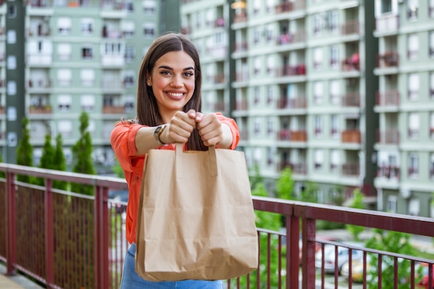 Donna che consegna cibo in sacco di carta. Servizio di consegna a domicilio.