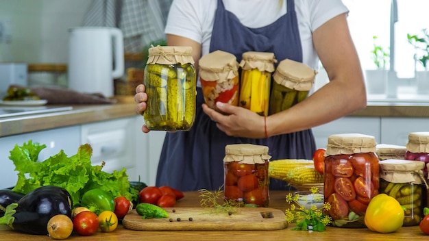 Donna che conserva verdure in barattoli in cucina Focalizzazione selettiva