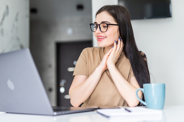 Donna che controlla le sue e-mail al mattino su un laptop mentre beve caffè