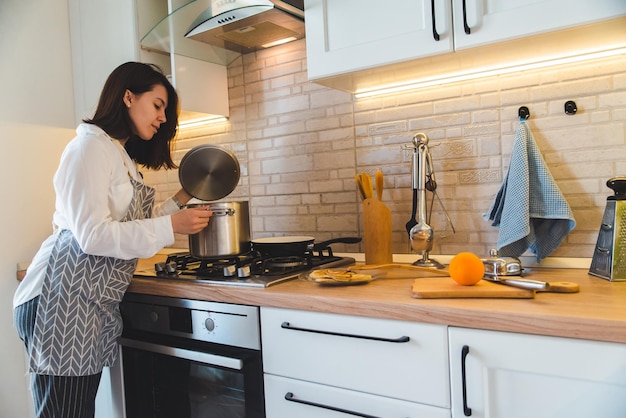 Donna che controlla pentola con acqua bollente in cucina