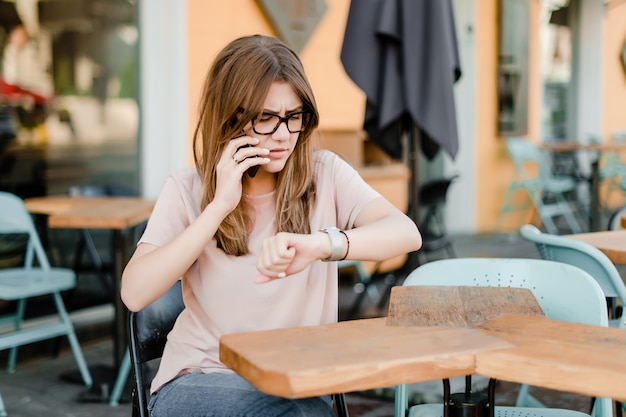 Donna che controlla tempo e che parla sul telefono