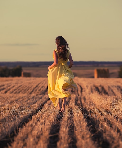 Donna che corre attraverso il campo al tramonto