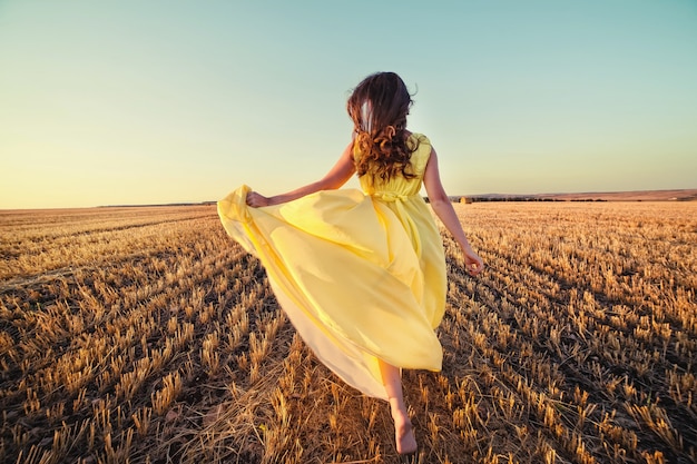 Donna che corre attraverso il campo al tramonto