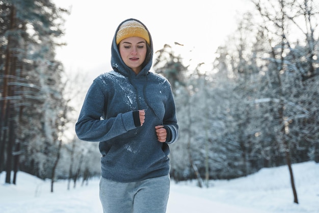 Donna che corre durante il suo allenamento da jogging durante l'inverno e le giornate nevose