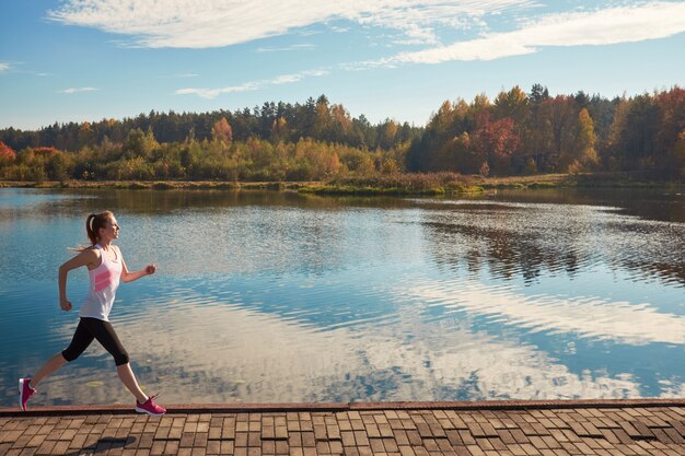 Donna che corre lungo un percorso con vista sul lago, stile di vita sano