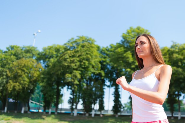 Donna che corre sulla pista dell'arena Allenatore o allenatore all'allenamento Runner sulla concorrenza e successo futuro Ragazza soleggiata all'aperto sul cielo blu Sport e fitness sano