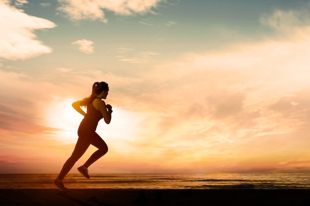 Donna che corre sulla spiaggia al tramonto o al tramonto