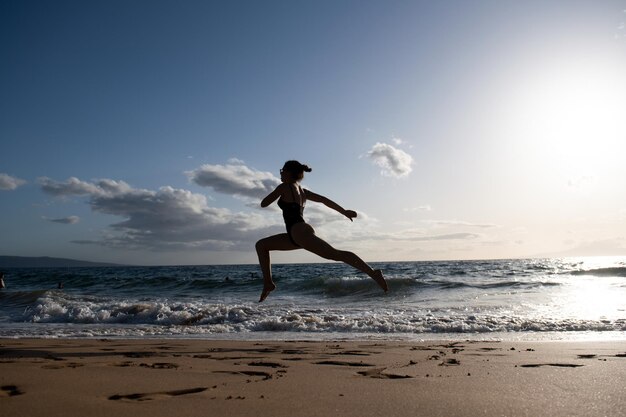 Donna che corre sulla spiaggia. Donna sana corsa in mare, ragazza che fa sport all'aperto, felice esercizio femminile, fitness e concetto di cura della brughiera su sfondo naturale.