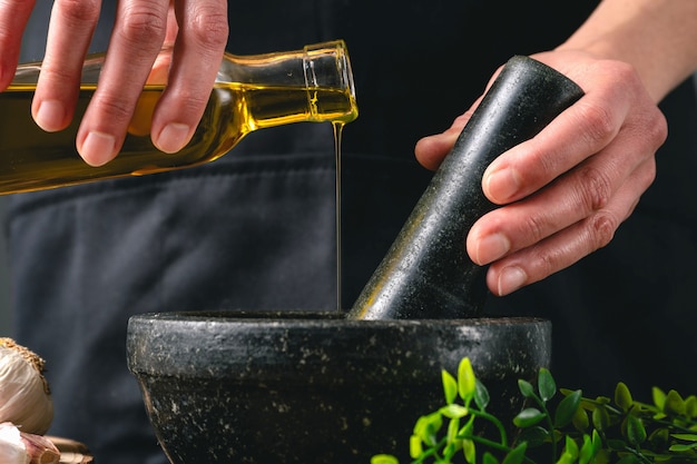 Donna che cucina con olio d'oliva e mortaio in cucina