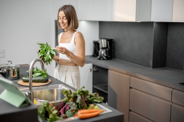 Donna che cucina con verdure fresche e verdure nel lavandino