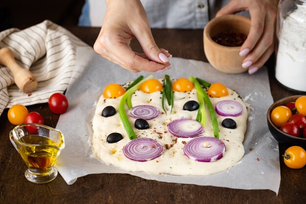 Donna che cucina focaccia italiana con verdure ed erbe Focaccia dell'orto