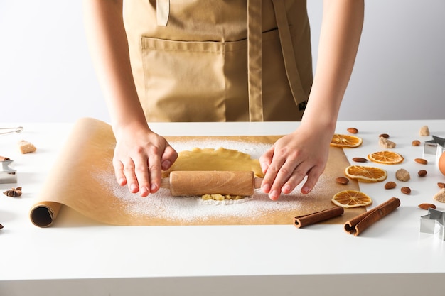 Donna che cucina i biscotti usando la taglierina del biscotto e il mattarello