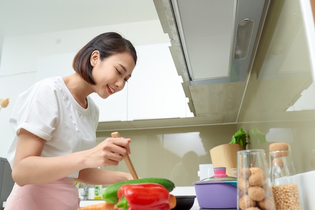 Donna che cucina in cucina con il cucchiaio di legno