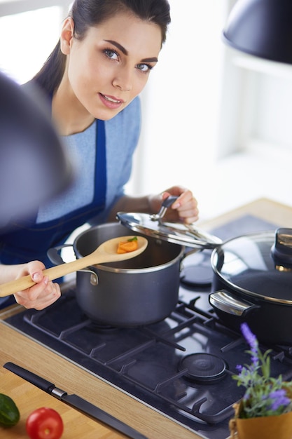 Donna che cucina in cucina con il cucchiaio di legno