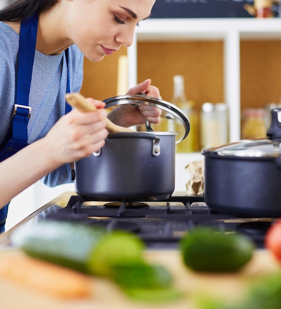 Donna che cucina in cucina con il cucchiaio di legno