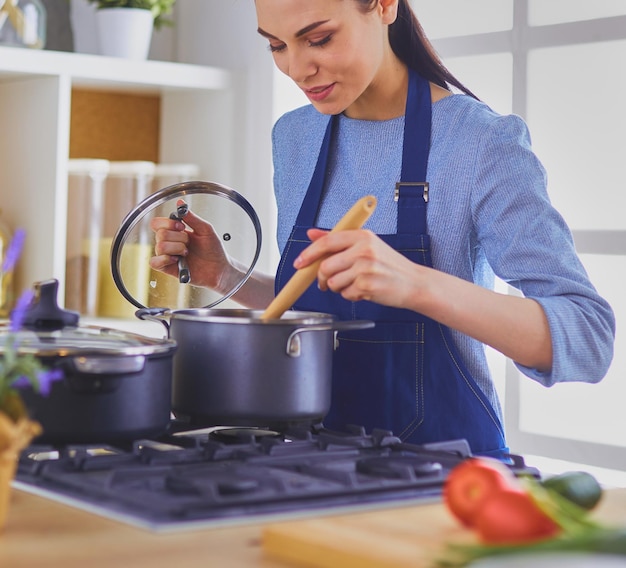 Donna che cucina in cucina con il cucchiaio di legno