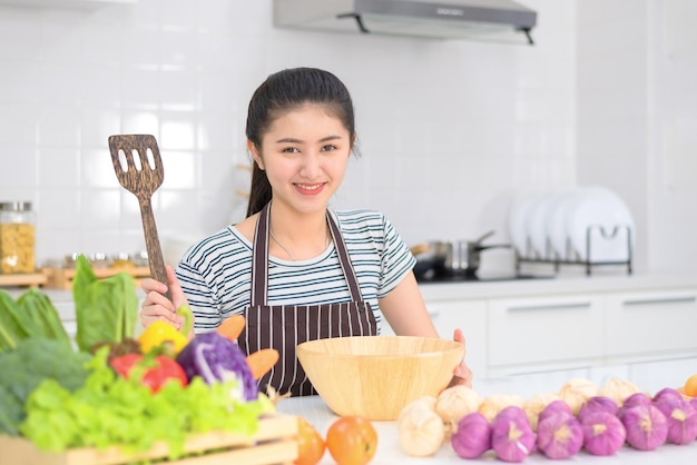 Donna che cucina in cucina, donne asiatiche cucinano con verdure, cucina bianca pulita.