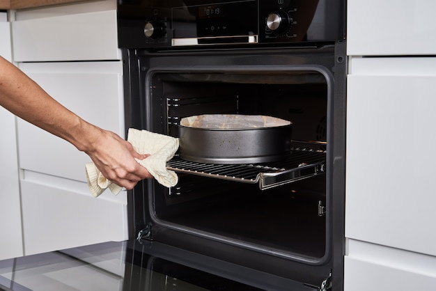 Donna che cucina la torta nel forno elettrico