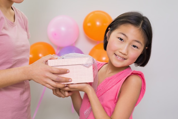 Donna che dà il contenitore di regalo ad una bambina ad una festa di compleanno