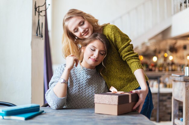 Donna che dà regalo alla sua ragazza nella caffetteria