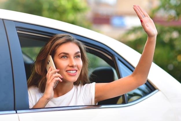 Donna che dà una occhiata dal finestrino dell'auto, donna che spunta dalla finestra e agitando la mano