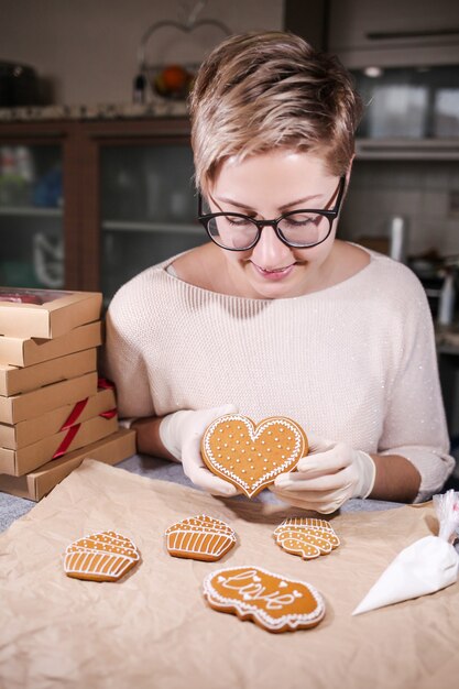 Donna che decora alcuni biscotti di panpepato fatti in casa in cucina