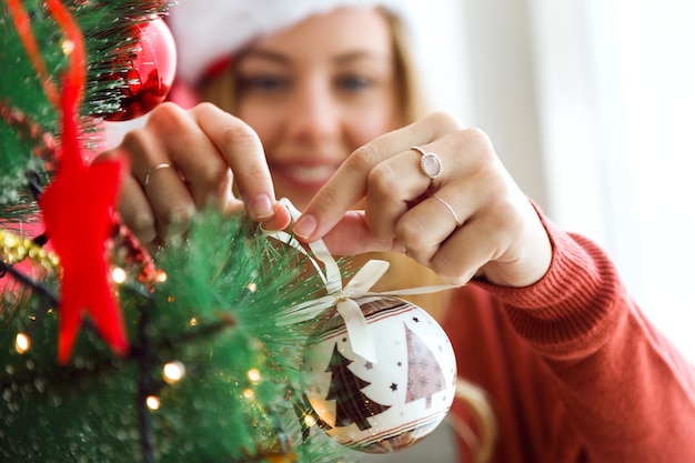 Donna che decora l&#39;albero di Natale con una palla bianca