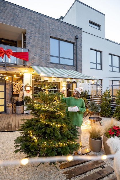 Donna che decora l'albero di Natale in cortile