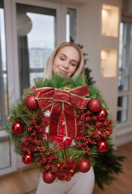 Donna che decora la casa per le vacanze di Natale Ghirlanda di Natale fatta da sé con messa a fuoco morbida