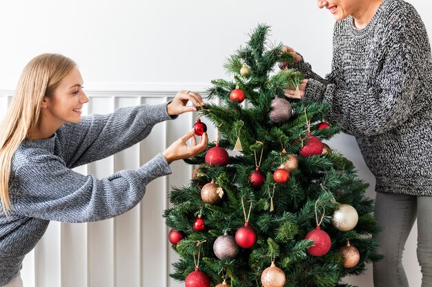 Donna che decora un albero di Natale con ornamenti