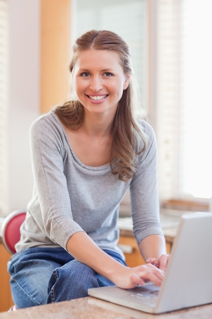 Donna che digita sul suo computer portatile in cucina