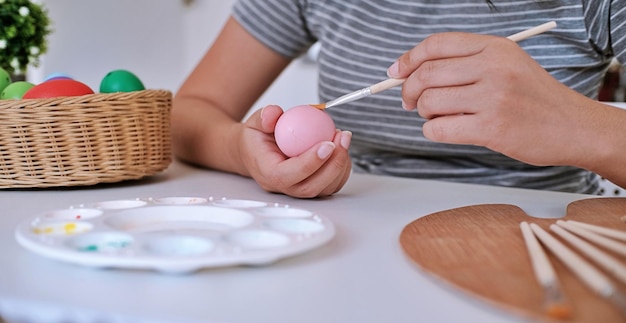 Donna che dipinge le uova di Pasqua a casa famiglia che si prepara per la Pasqua Mani di una ragazza con un uovo di Pasqua