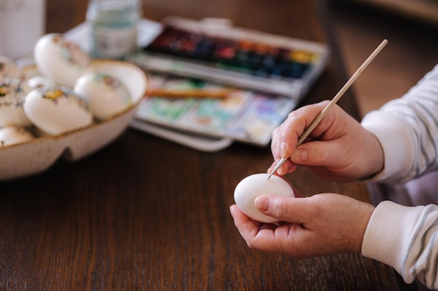 Donna che dipinge un acquarello sulle uova di gallina fantasia per il festival dell'uovo di Pasqua femminile che disegna poco