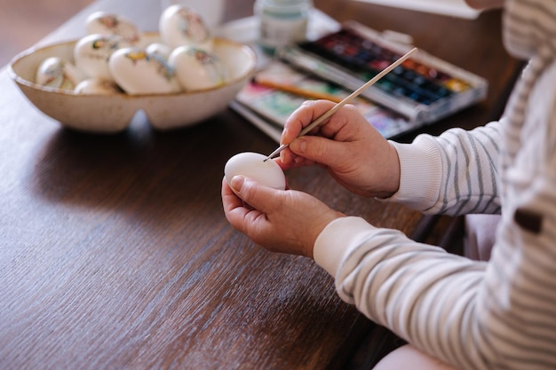 Donna che dipinge un acquarello sulle uova di gallina fantasia per il festival dell'uovo di Pasqua femminile che disegna poco