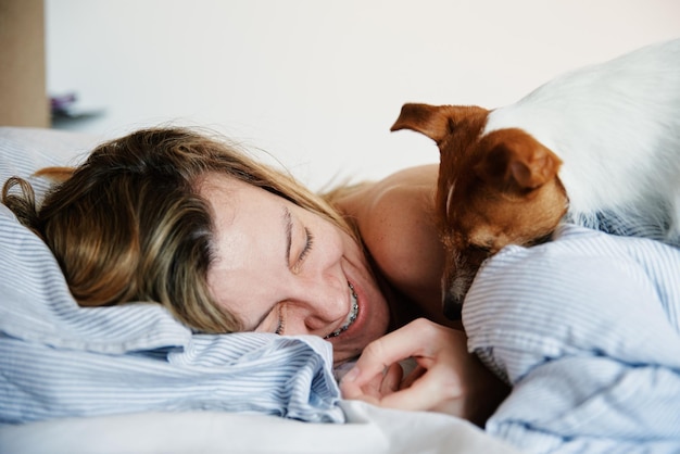 Donna che dorme a letto e gioca con il suo cane