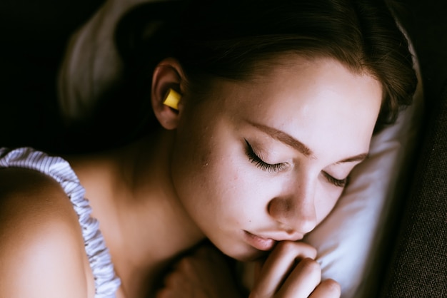 Donna che dorme con i tappi per le orecchie nelle orecchie