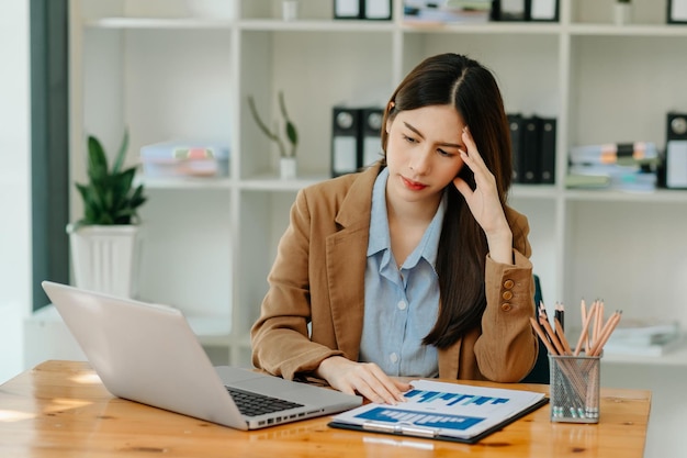 Donna che è stanca e pensa troppo per aver lavorato con tablet e laptop al moderno officexA